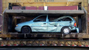 The van on the car crusher with the rear bumper falling off.