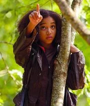 From her spot in a tree, Rue points out the tracker jacker nest to Katniss.