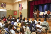 Ava makes an announcement during the school assembly.
