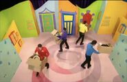 The Wiggles running around while holding boxes of hats