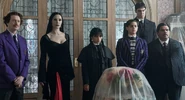 Barry Dort, Morticia Addams, Wednesday Addams, Pugsley Addams, Lurch, and Gomez Addams standing in a room
