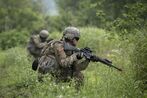 An image of two soldiers crouched in a grassy field.