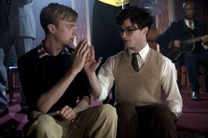 Lucien Carr (Dane DeHaan, Left) and Allen Ginsberg (Daniel Radcliffe, Right), both have their hands held out as if to 'high-five'. Allen's palm is visible to the audience reveling a gash down the center, Lucien is holding the knife they used with his other hand. The characters are performing a 'Blood Oath' while at a party.