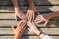 76196905-from-above-view-of-crop-hands-of-five-people-putting-hands-together-on-table-