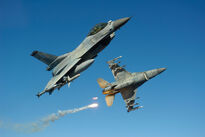 Two F-16C Block 50 manoeuvring and dumping flares.