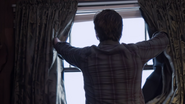 Jake opens the curtains of his motel room.