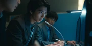 Ryuji speaks into a microphone in a control room, focused on the conversation
