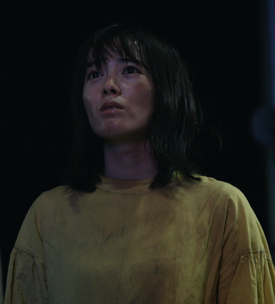 A screenshot of Natsuki from Season 2, a woman wearing a long-sleeved yellow shirt