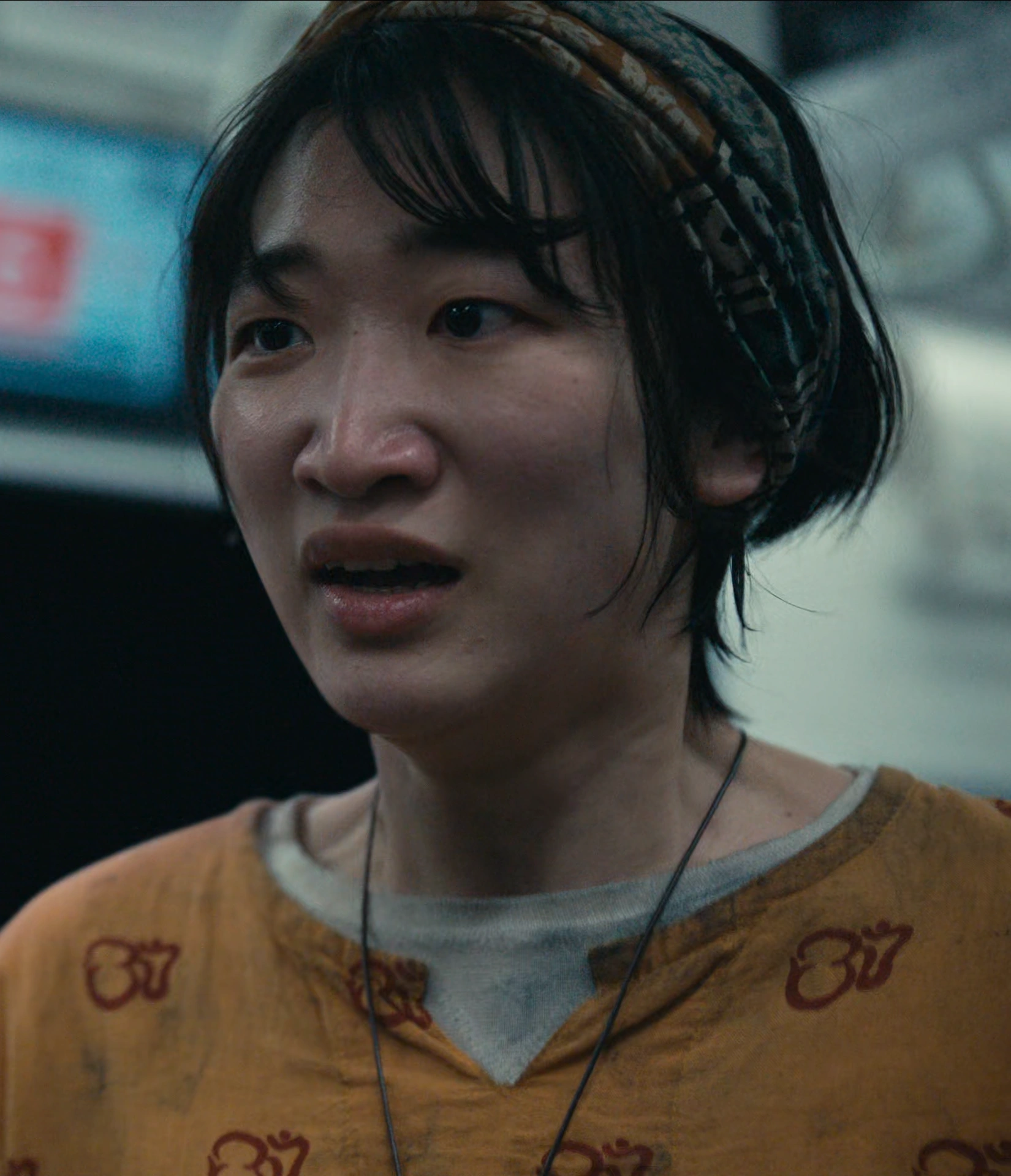 A screenshot of Juri from Season 3, a young woman wearing a headband and a bright orange top, looking shocked and desperate