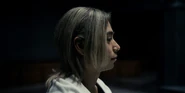 A side view close-up of Chishiya turned slightly right, his lips forming a faint smile in the dim light