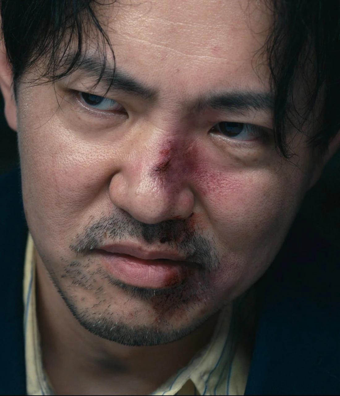 A middle-aged man in a dark blue suit with a yellow shirt underneath