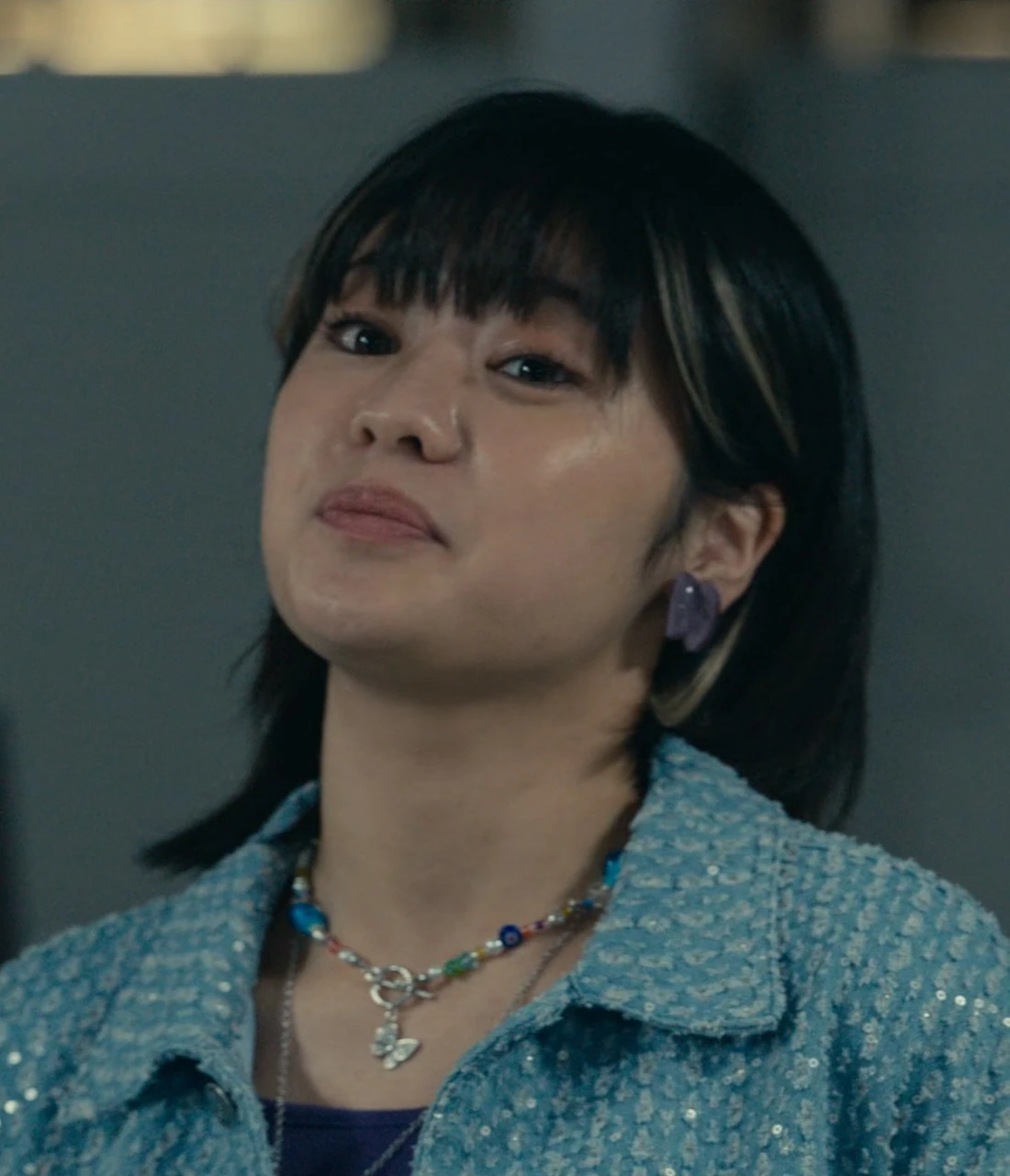 A close-up shot of Natsu wearing a beaded necklace and looking upwards confidently