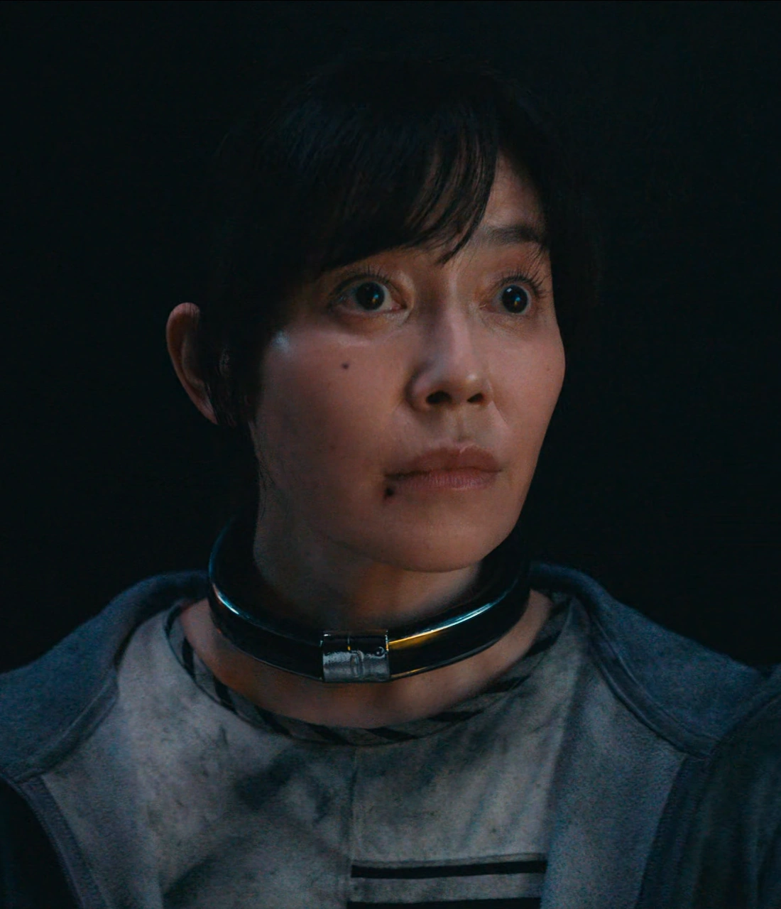 A close-up shot of Sachiko staring ahead with wide eyes, her face slightly bruised