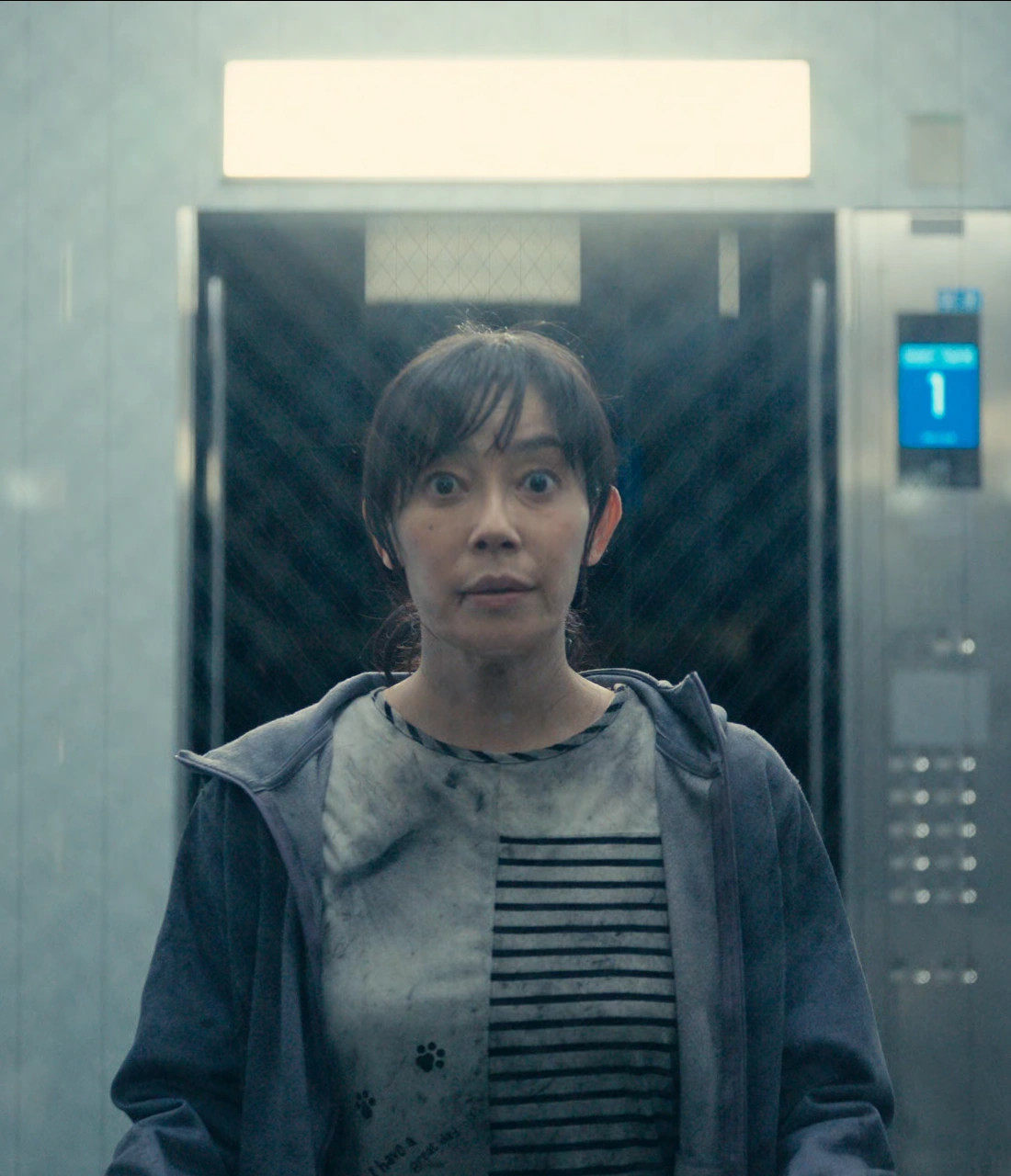 A close-up shot of Sachiko in the elevator, looking through the transparent walls with confusion
