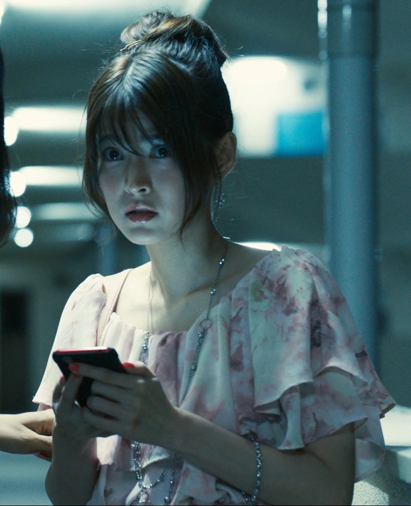 A screenshot of Mai from Season 1, a young woman with long hair in a tail, wearing a white & pink blouse