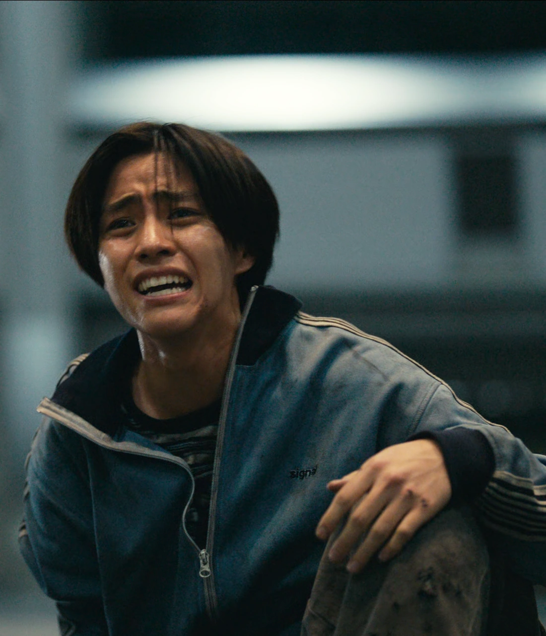 A close-up shot of Nobu, sitting on the floor after clearing the round, looking apologetic