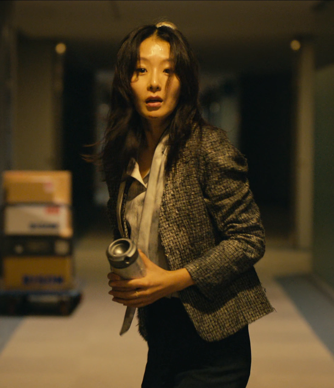 A screenshot of Shion in a hallway, holding a can and looking back with a lost expression