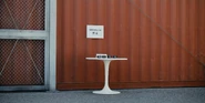 Table with wristbands (King of Clubs).jpg (1.48 MB) A white table by a shipping container wall, four wristbands on top of it