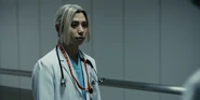 A front-facing shot of Chishiya in his doctor coat, standing in the hallway with a surprised expression