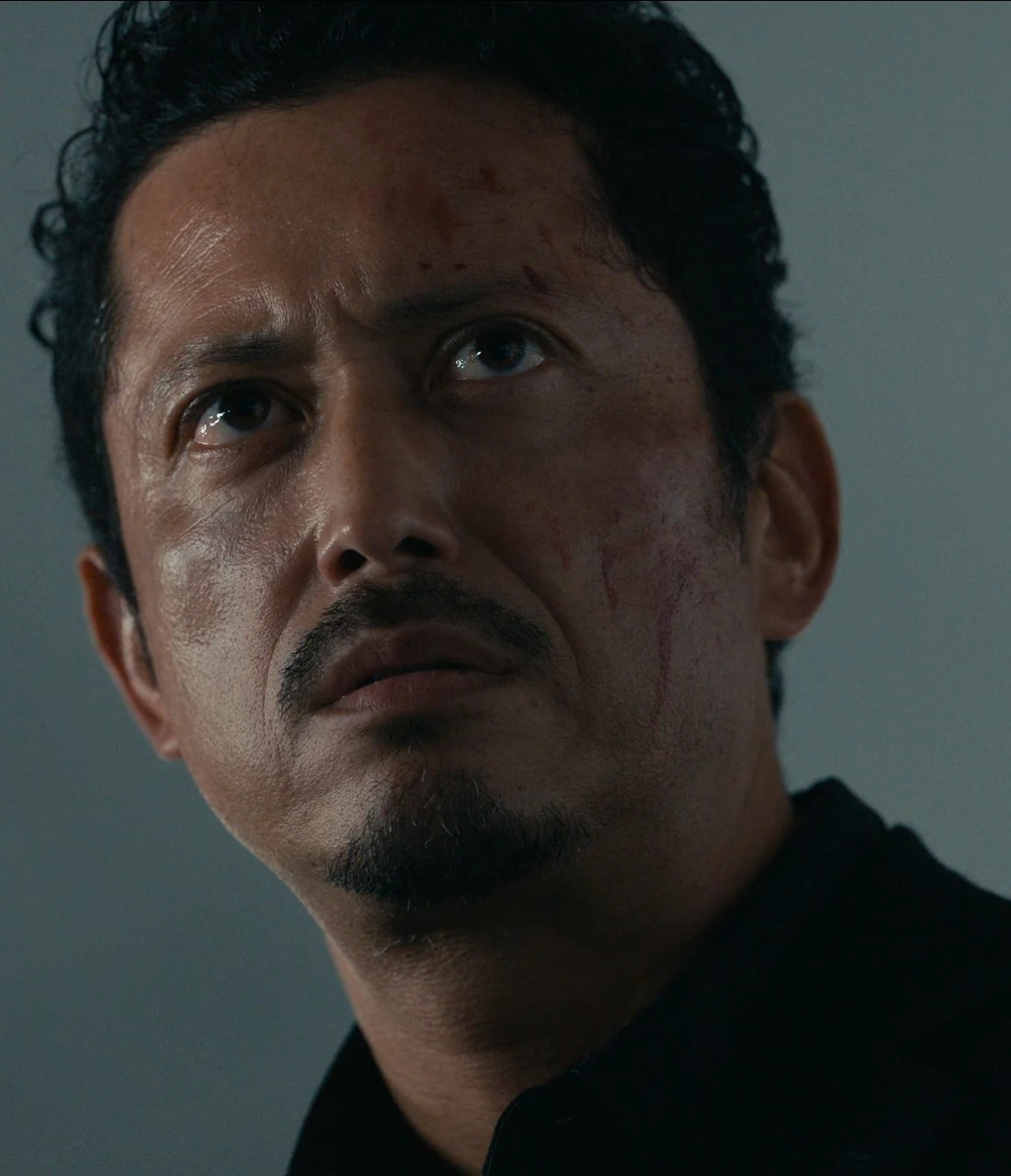 A close-up shot of Kazuya with a serious expression and blood on his face