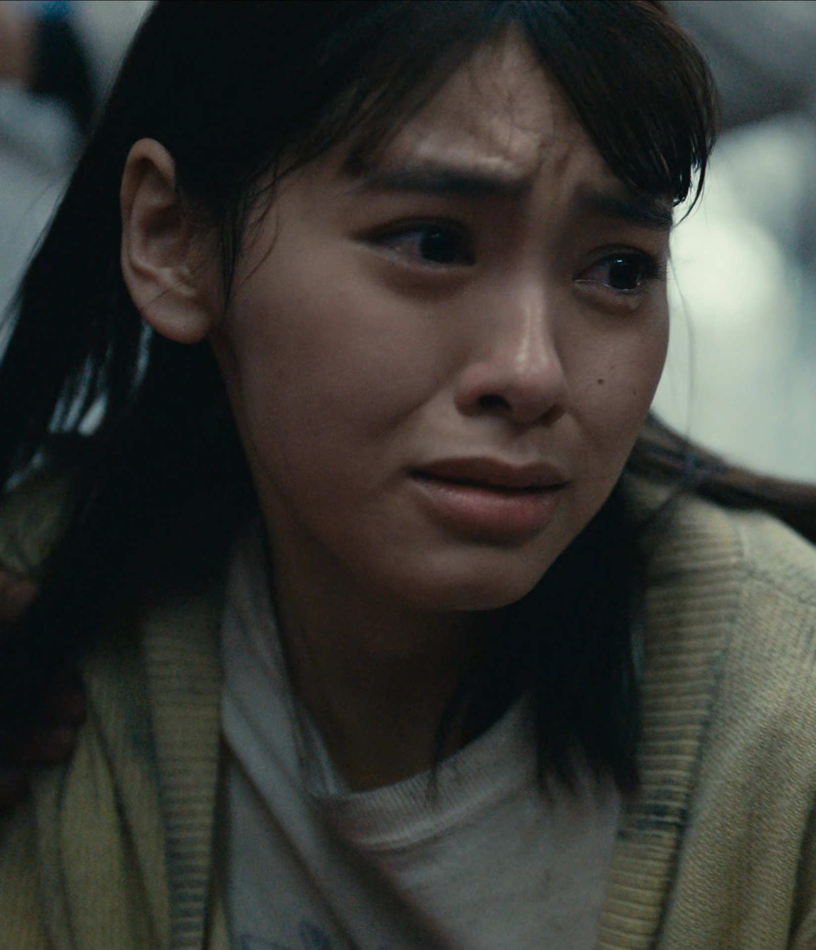 A screenshot of Yuna Itsuki from Season 3, a young woman with short straight hair in a yellow cardigan, crying from fear