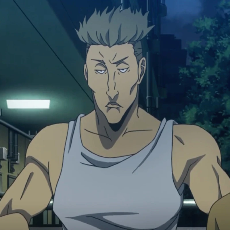 A young muscular man looking to his right. He has bleached hair with buzzed sides, tanned skin, and wearing a white tank top