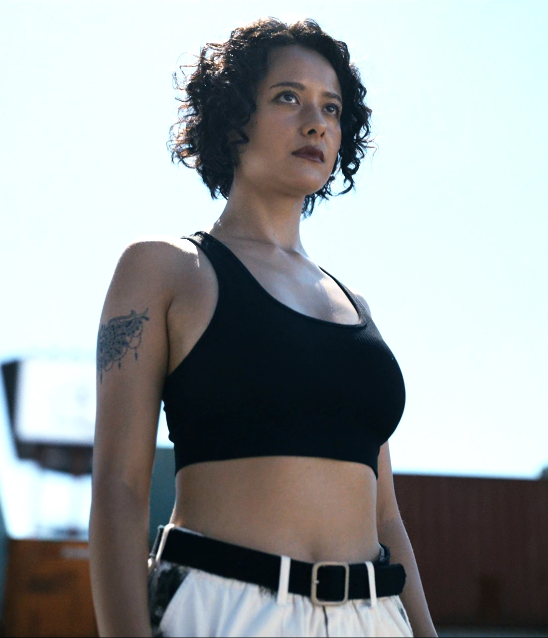 A screenshot of Uta from Season 2, a woman wearing a black crop-top and white trousers