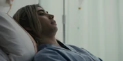 A close-up shot of Chishiya lying on a hospital bed with a puzzled look on his face