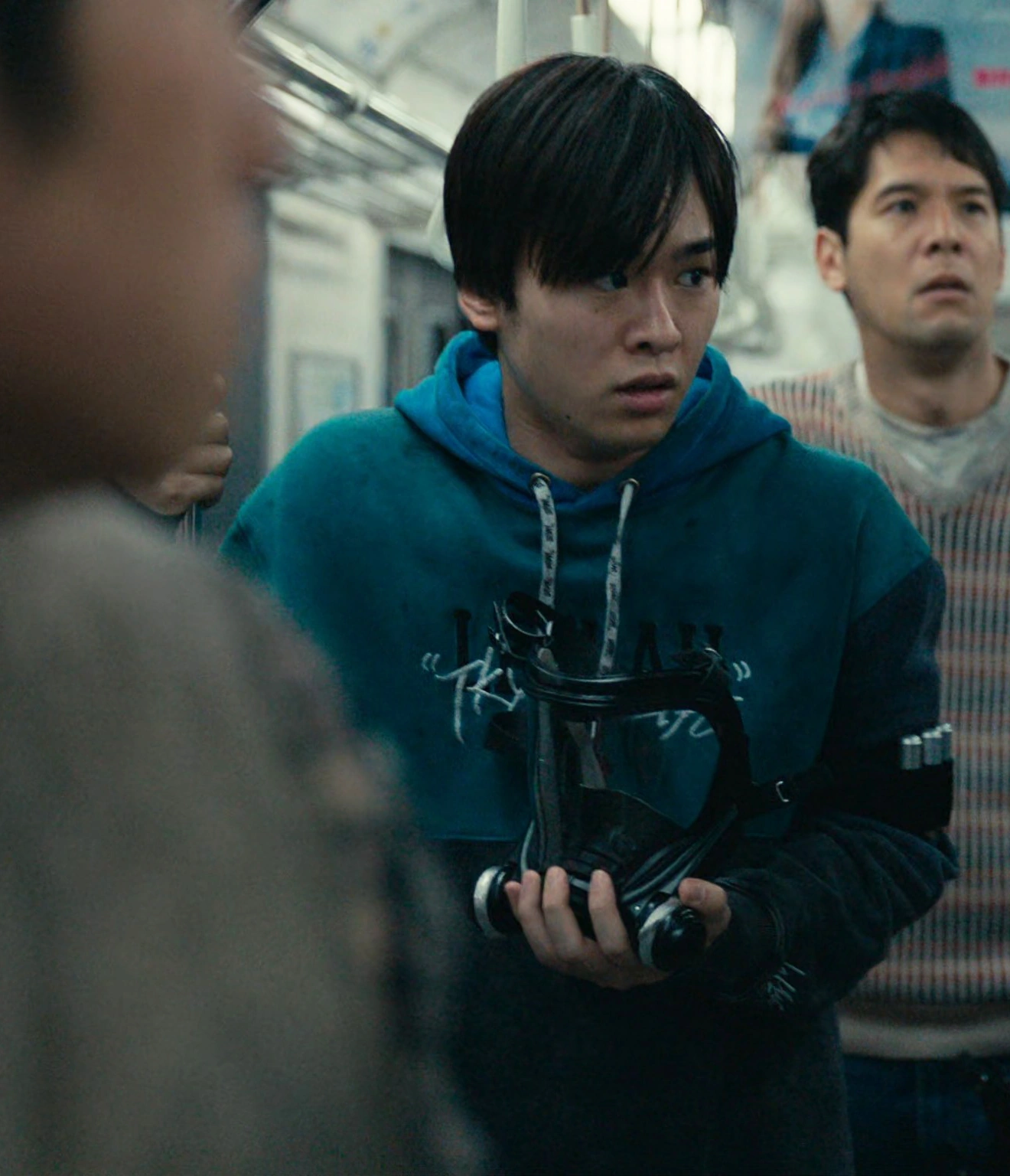 A screenshot of an unnamed male player wearing a blue hoodie and holding onto a grab pole