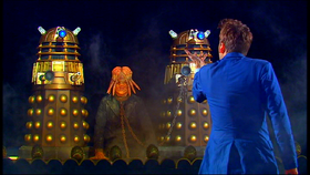 The Doctor stands before the Daleks - with Sec in chains.