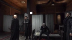 Crowley, Hamet, and Scoff discuss their next move while Paddington sits up on his cot.