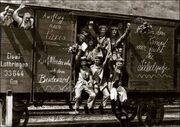 Men waving from the door and window of a rail goods van