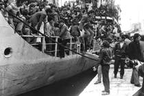 Italian refugees starting to disembark from one of the first ships that docked in Montevideo alongside others, they are helped by Uruguayan citizens.