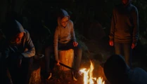 They take her to a campfire site and take off the bag