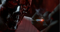 Black Mask about to burn out one of Warden Joseph's eyes with a lit cigarette
