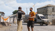 Aid worker (left) wearing an Identification Vest with the IDAP logo.