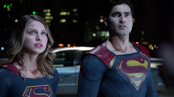 Supergirl e Superman conversando com um homem