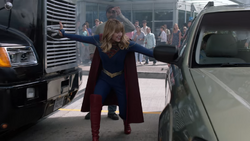 Supergirl impedindo um caminhão atingir um carro