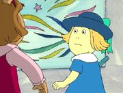 Emily wearing a blue dress with a white collar and a dark blue hat with a turquoise bow.