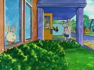 When he looks out the window, the poster is being carried in the door from the road, meaning that it wouldn't have gone past the window