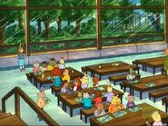 The students eating their lunch on the other side of the cafeteria as the puke is being cleaned.