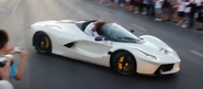 White LaFerrari Aperta doing a burnout in a large crowd.