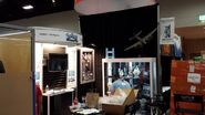 The Prop Store setting up their SDCC 2013 booth. Weaver's Flame Thrower prop can be glimpsed in the bottom of the cabinet.[17]