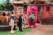 Barney stands next to the children wearing silly hats.