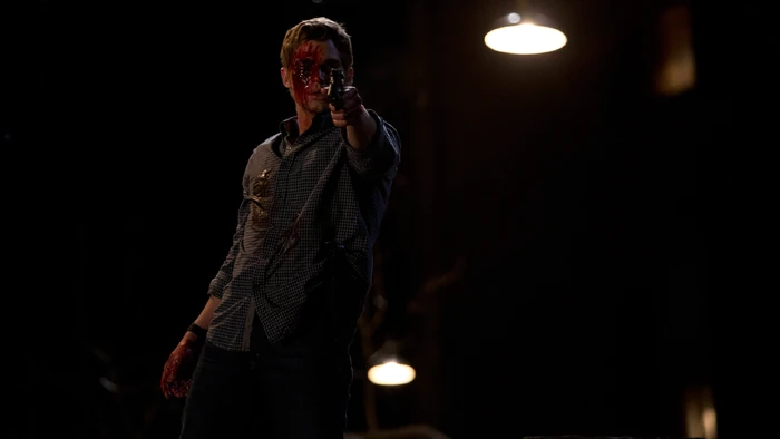 It's Shelby. Despite his horrible injury, he raises his gun and points it at Norma.