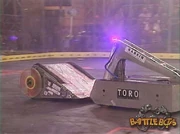 Atomic Wedgie starts pushing the now incapacitated Toro.