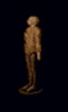 A humanoid statue facing left on a black background. The statue is made of brown wood and has a featureless head, a long tunic, slender legs, and a circular wooden base.