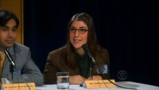 Amy sits next to Raj as a member of the panel at a science symposium.