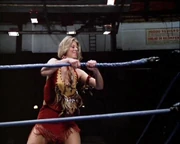 Jaime snaps off turnbuckle rope with her bionic arm.