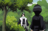 Byakuya walks forward from behind a tree and a bush.